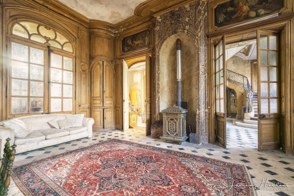 Photographie d'un salon de château contenant un canapé et une cheminée.