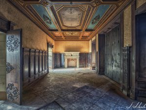 Photographie d'un couloir de château avec un plafond à reliefs.