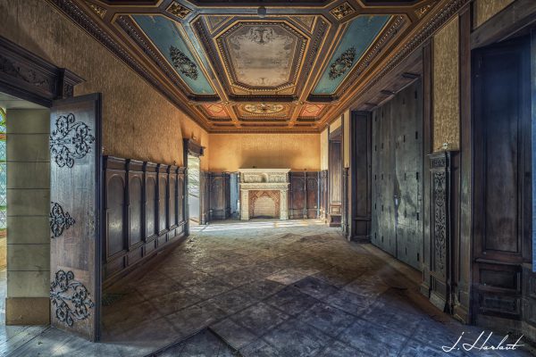 Photographie d'un couloir de château avec un plafond à reliefs.