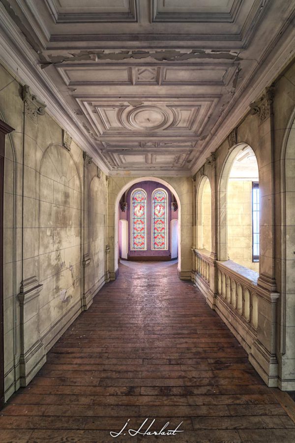 Photographie d'un couloir de château avec un plafond à reliefs.