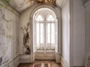 Photographie d'une fenêtre d'une chambre d'un château abandonné.