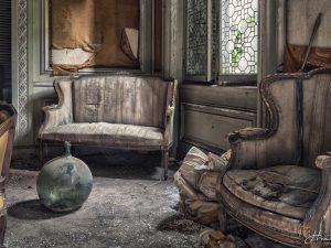 Photographie d'un salon abandonné avec deux fauteuils et un vase