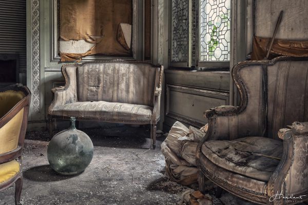 Photographie d'un salon abandonné avec deux fauteuils et un vase