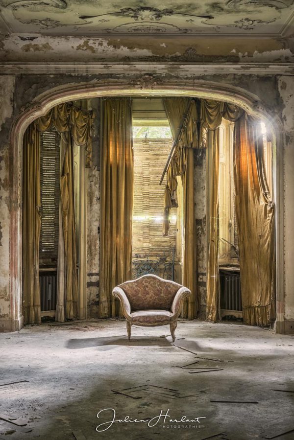 Photographie d'un fauteuil placé au centre d'une chambre d'une villa abandonnée.