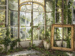 Photographie d'un cadre doré placé dans une pièce vitrée.
