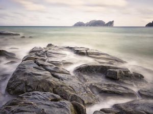 Photographie d'un bord de mer où l'eau se mélange avec la brume.