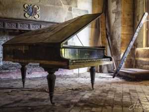 Photographie d'un vieux piano Pleyel dans une pièce abandonnée.