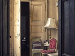 Photographie prise depuis un couloir montant une pièce avec une porte entre-ouverte.