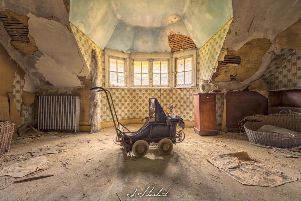 Photographie d'un landau dans une chambre délabrée.
