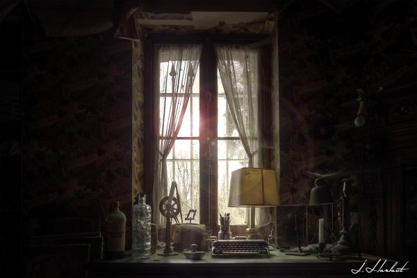 Photographie de la fenêtre du bureau d'écriture laissant entrer la lumière dans cet espace sans vie.