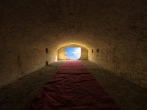 Photographie d'un couloir avec au bout une ouverture sur l'extérieur.