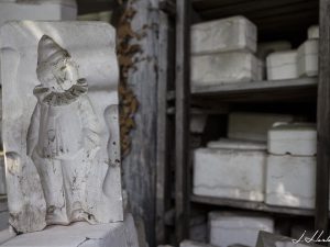 Photographie d'un moule de clown en céramique trouvée dans une salle contenant d'autres moules et sculptures.