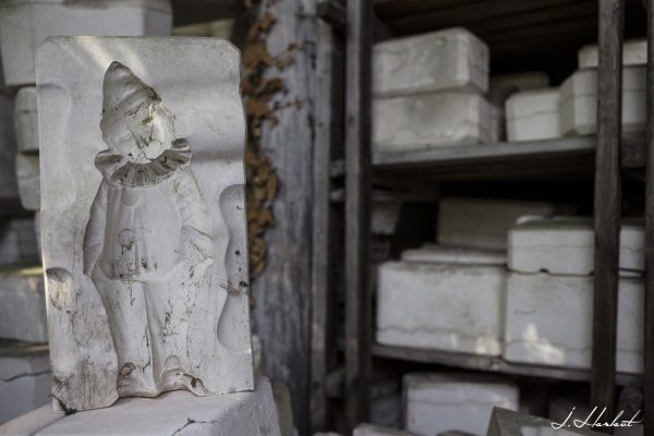 Photographie d'un moule de clown en céramique trouvée dans une salle contenant d'autres moules et sculptures.