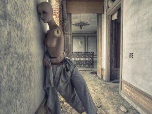 Photographie d'un mannequin abandonnée et détérioré dans un couloir de maison.