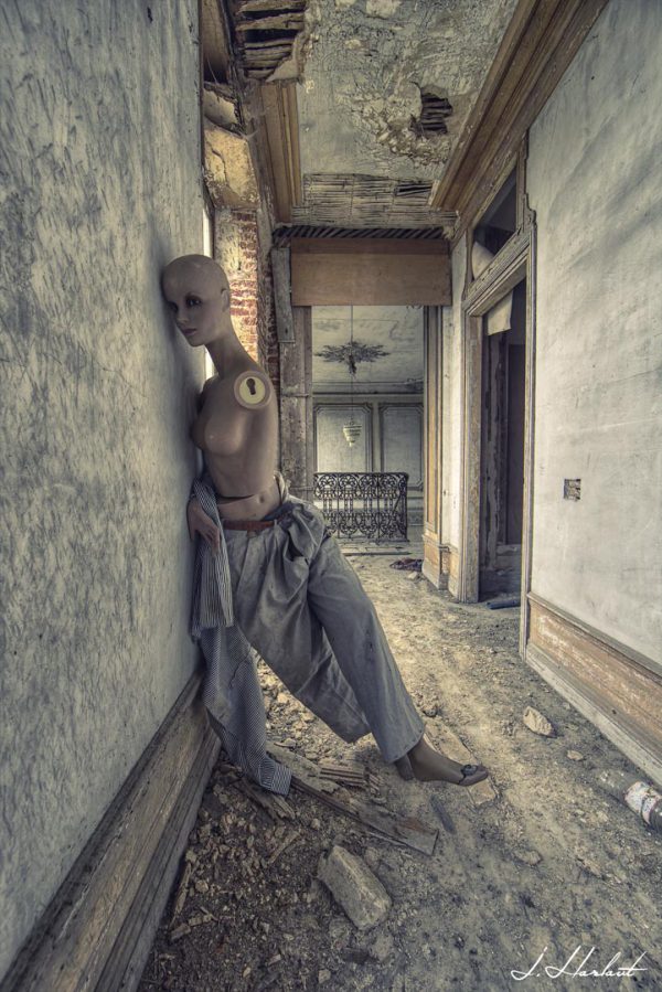 Photographie d'un mannequin abandonnée et détérioré dans un couloir de maison.