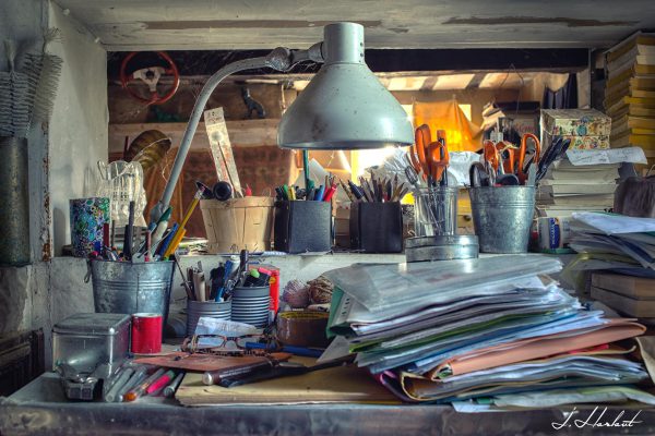 Photographie d'un bureau de travail avec des crayons, des dossiers et autres objets.